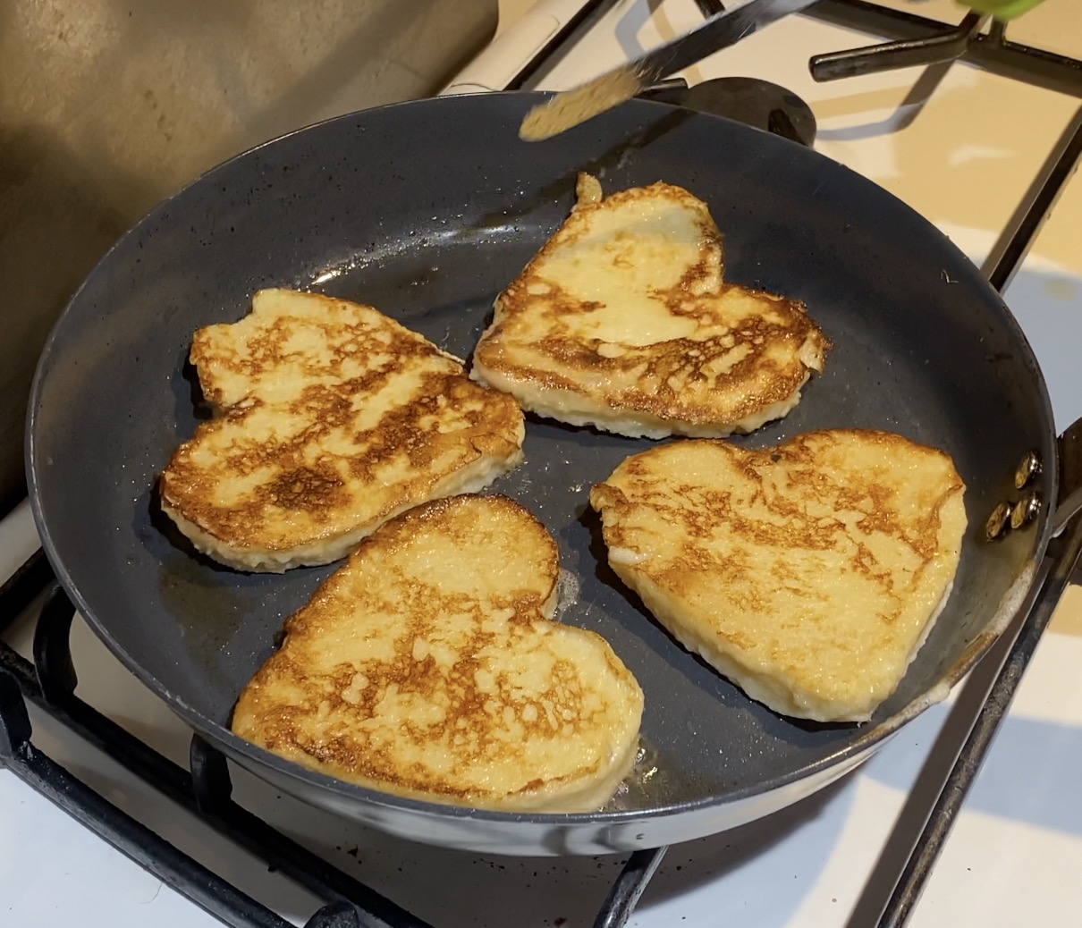 A fry pan with heart shaped French Toast.