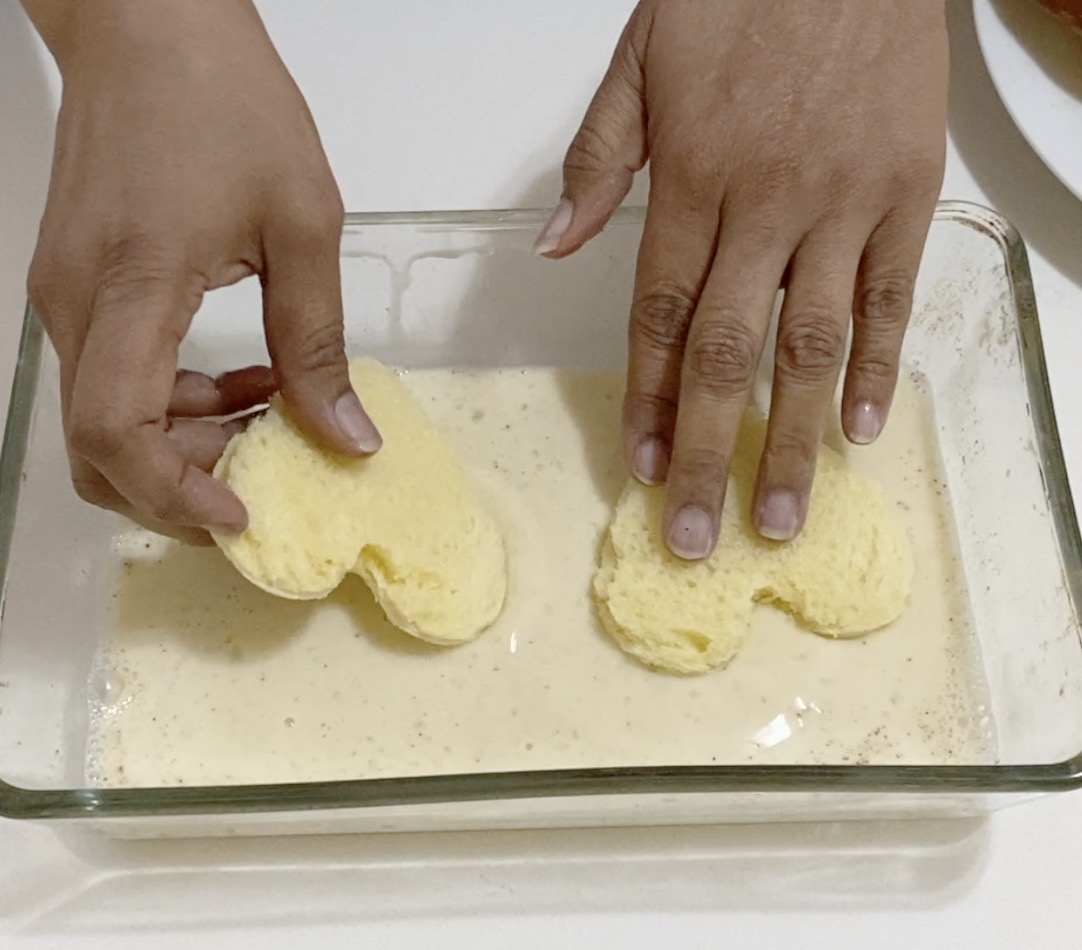 A shallow dish with soaking French Toast Hearts.