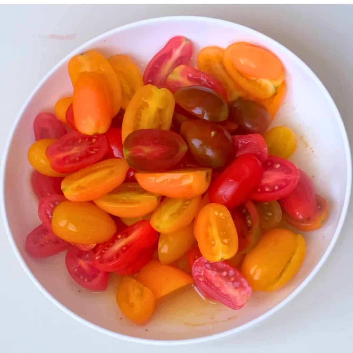A white bowl with fresh cherry tomato halves.