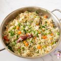 A saute pan with pilaf and veggies