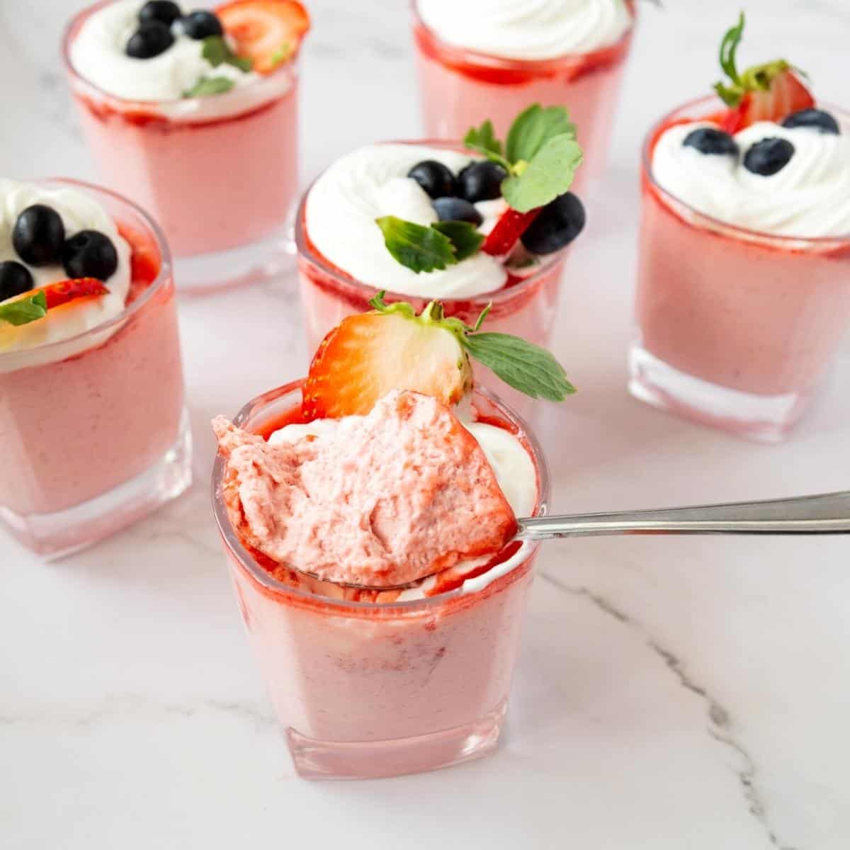 Glasses with mousse with strawberry and whipped cream.