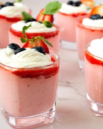 Glasses with mousse with strawberry and whipped cream.