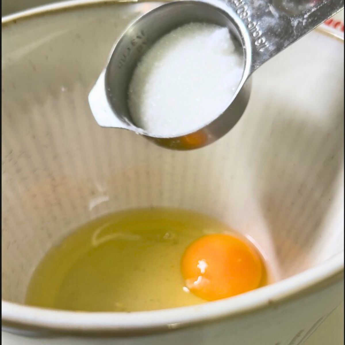 Adding sugar to eggs in pancake batter.