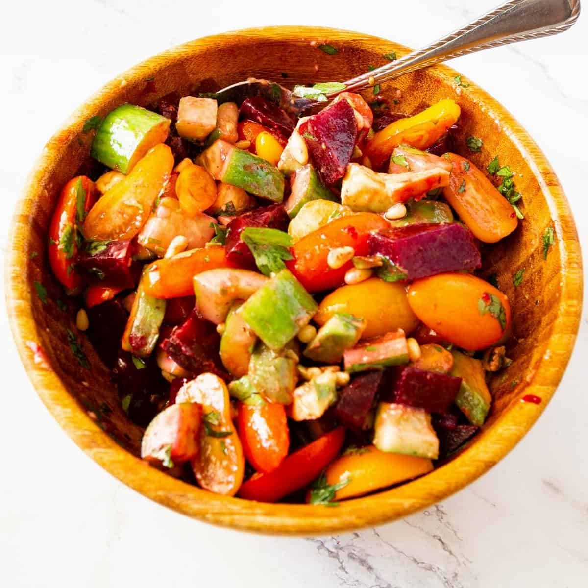 Beet salad recipe in a bowl with cherry tomatoes and avocado.