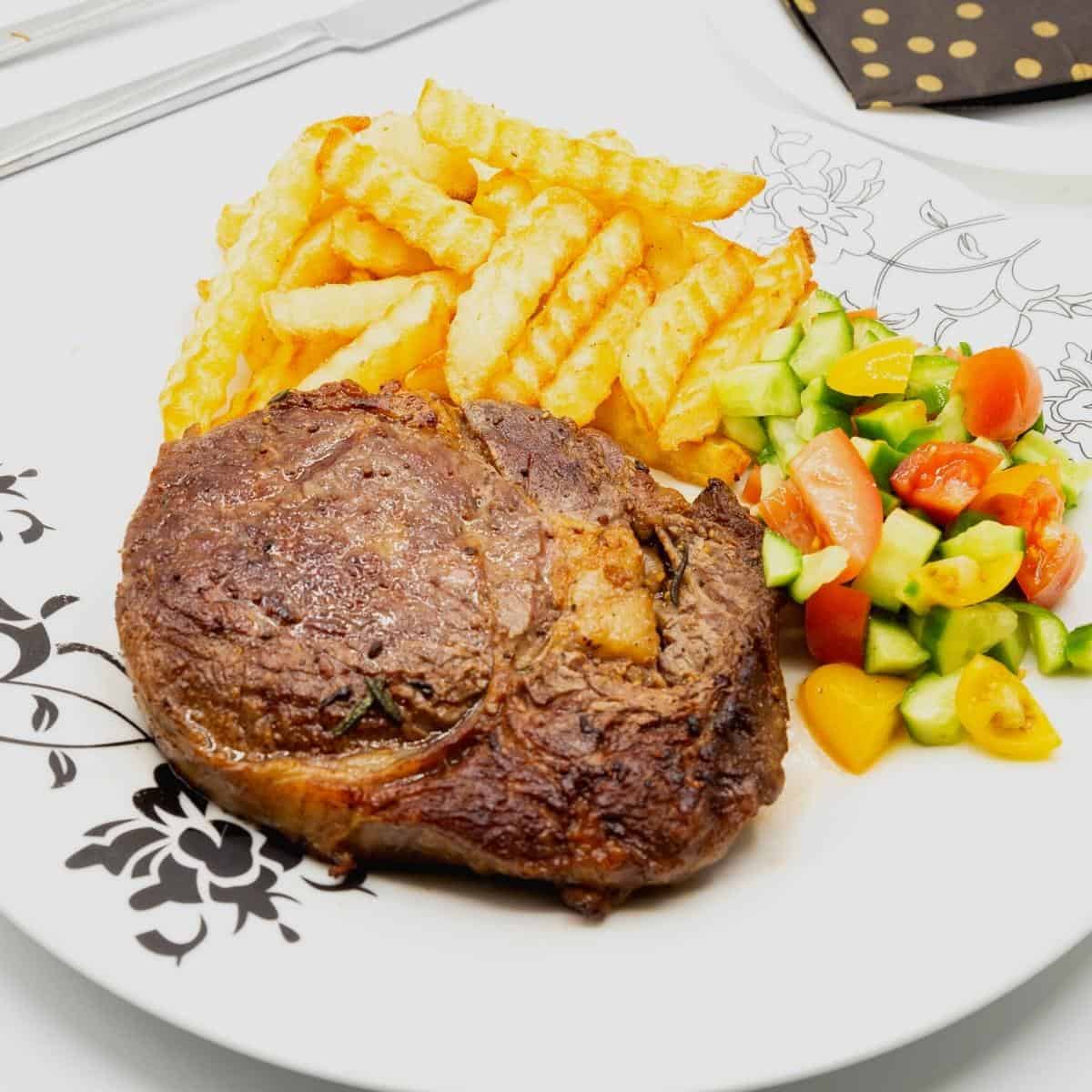 Steak on a plate with fries and salad.