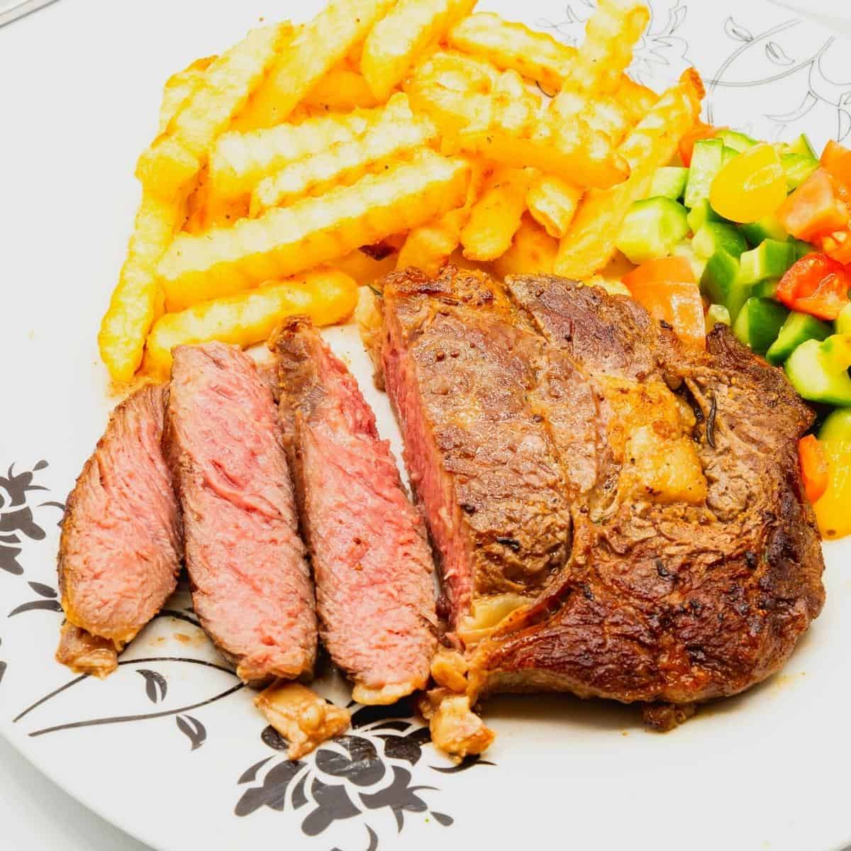 A plate with steak medium rare, fries and salad.