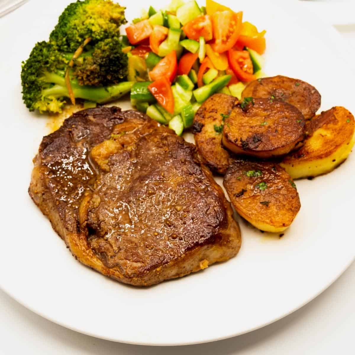 A plate with steak, melting potatoes, and veggies.
