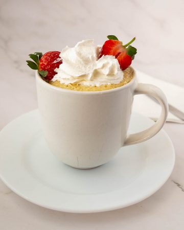 Vanilla cake in a mug topped with whipped cream