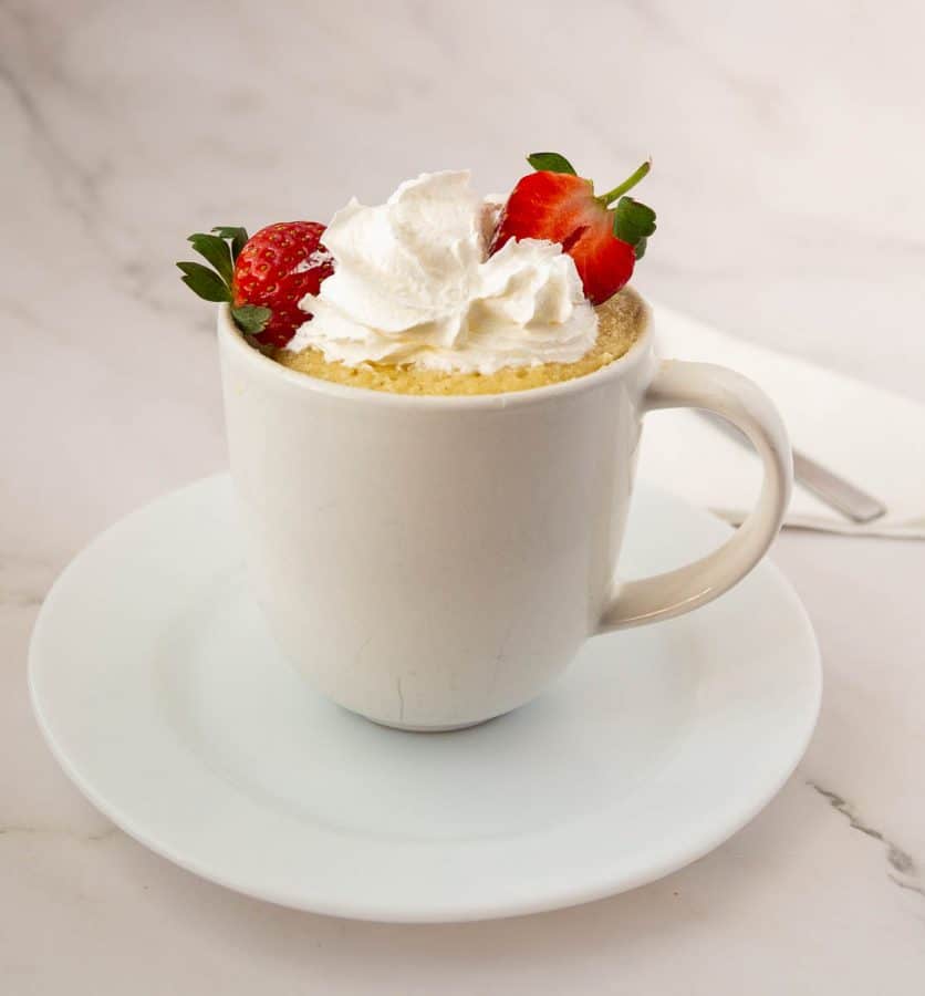 Vanilla cake in a mug topped with whipped cream