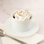 Chocolate mug cake in a ramekin topped with whipped cream.