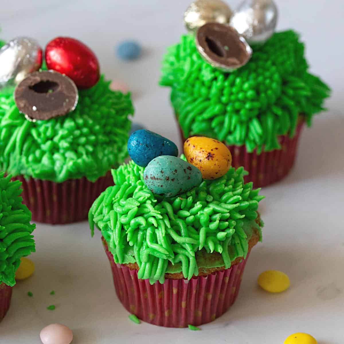 Cupcakes with green grass frosting and eater eggs.