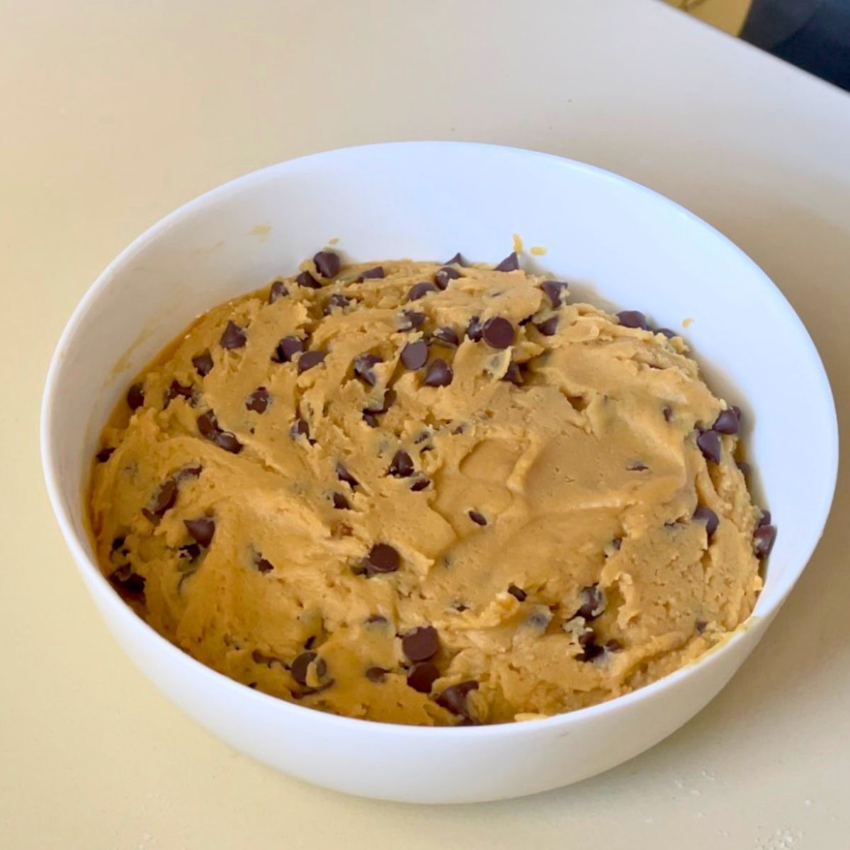 A white bowl with chocolate chip cookie dough.