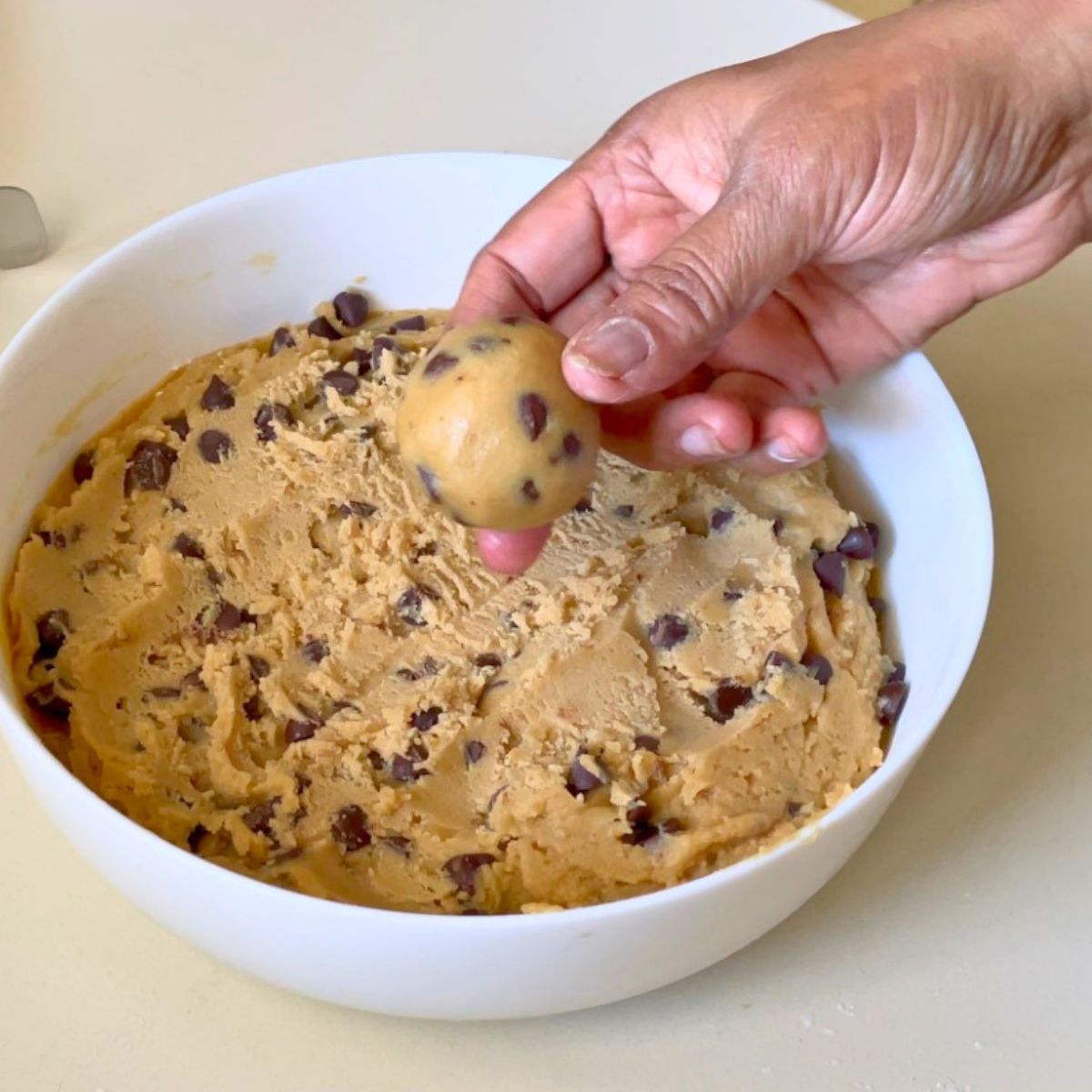 A chocolate chip cookie dough in white bowl.