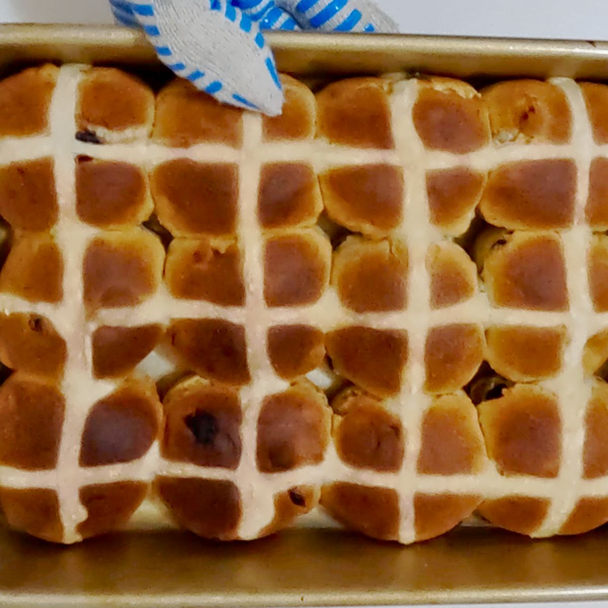 Baked hot cross buns with flour cross in baking pan.