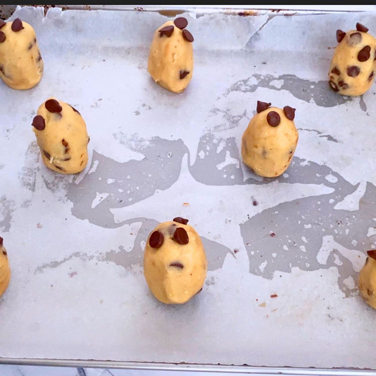 A baking tray with tall cookie dough balls for baking.