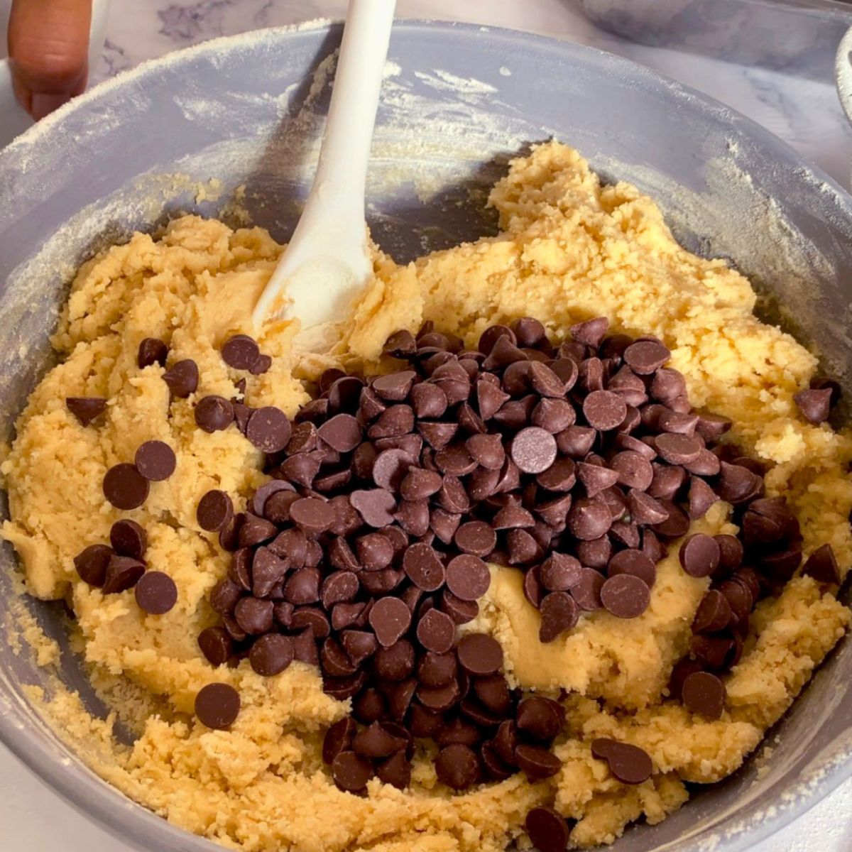 Adding chocolate chips to the cookie dough.