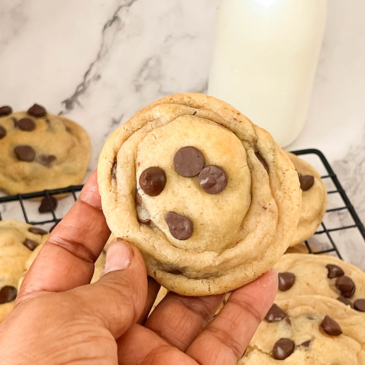 Hold a fresh baked chocolate chip cookies in hand.