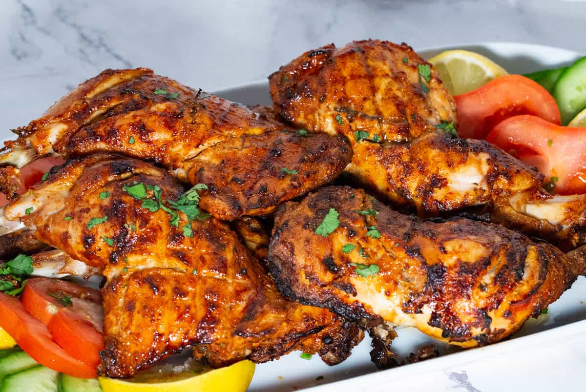 A platter with chicken quarters with tandoori marinade.