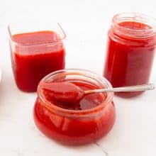 Prepared strawberry jelly in a jar with spoon.