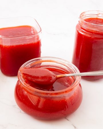 Prepared strawberry jelly in a jar with spoon.