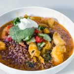 A white plate with shrimp curry and buckwheat.