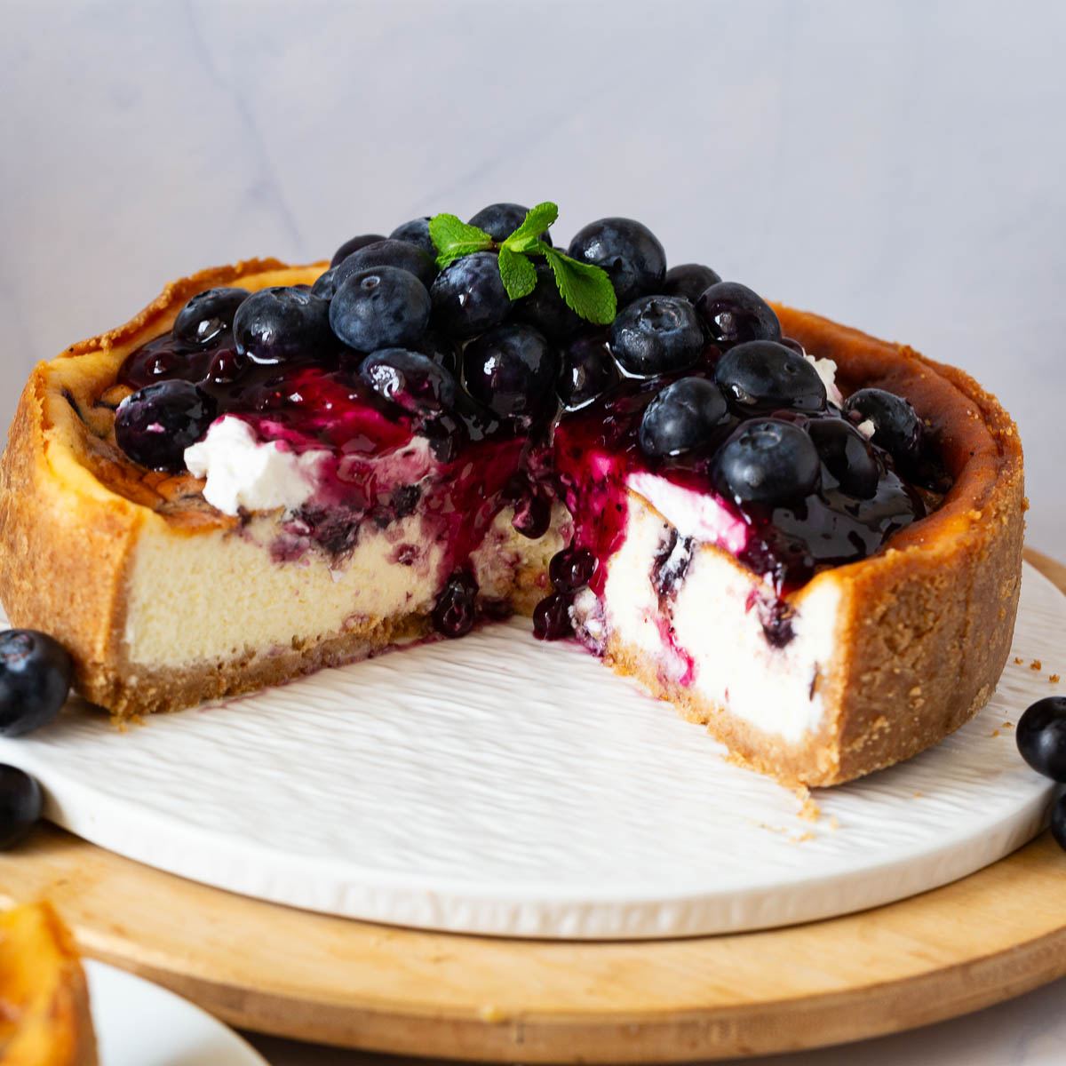 A baked blueberry cheesecake on the cake stand.