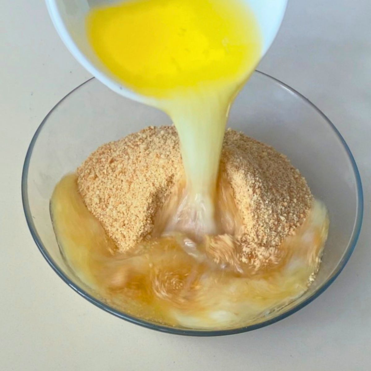 Adding melted butter to the cookie crust.