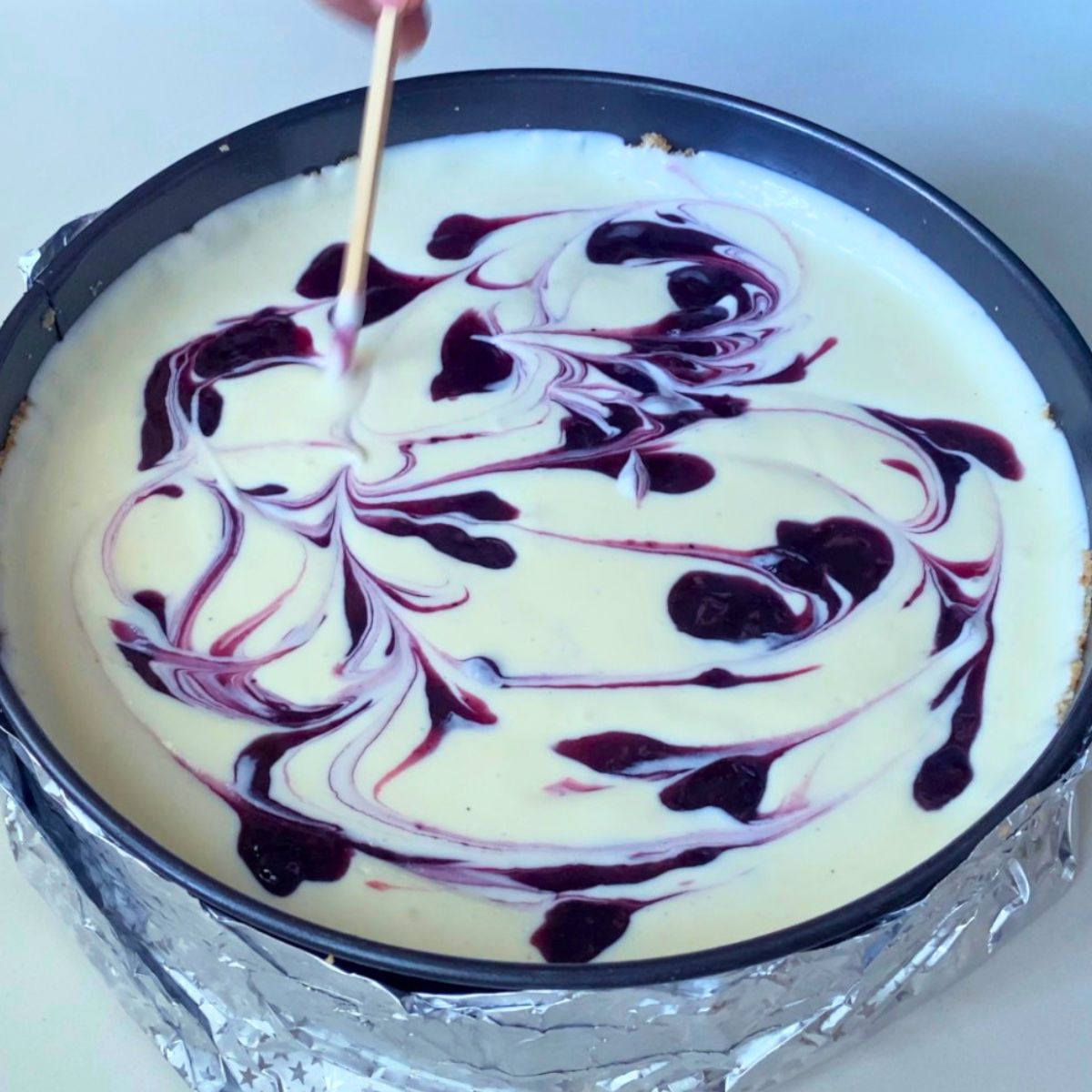 A spring form pan with blueberry swirl.