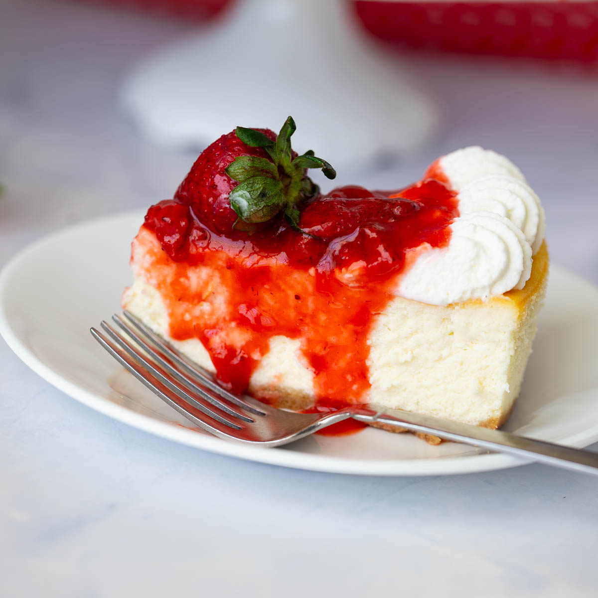 A frosted strawberry cheesecake on the table.