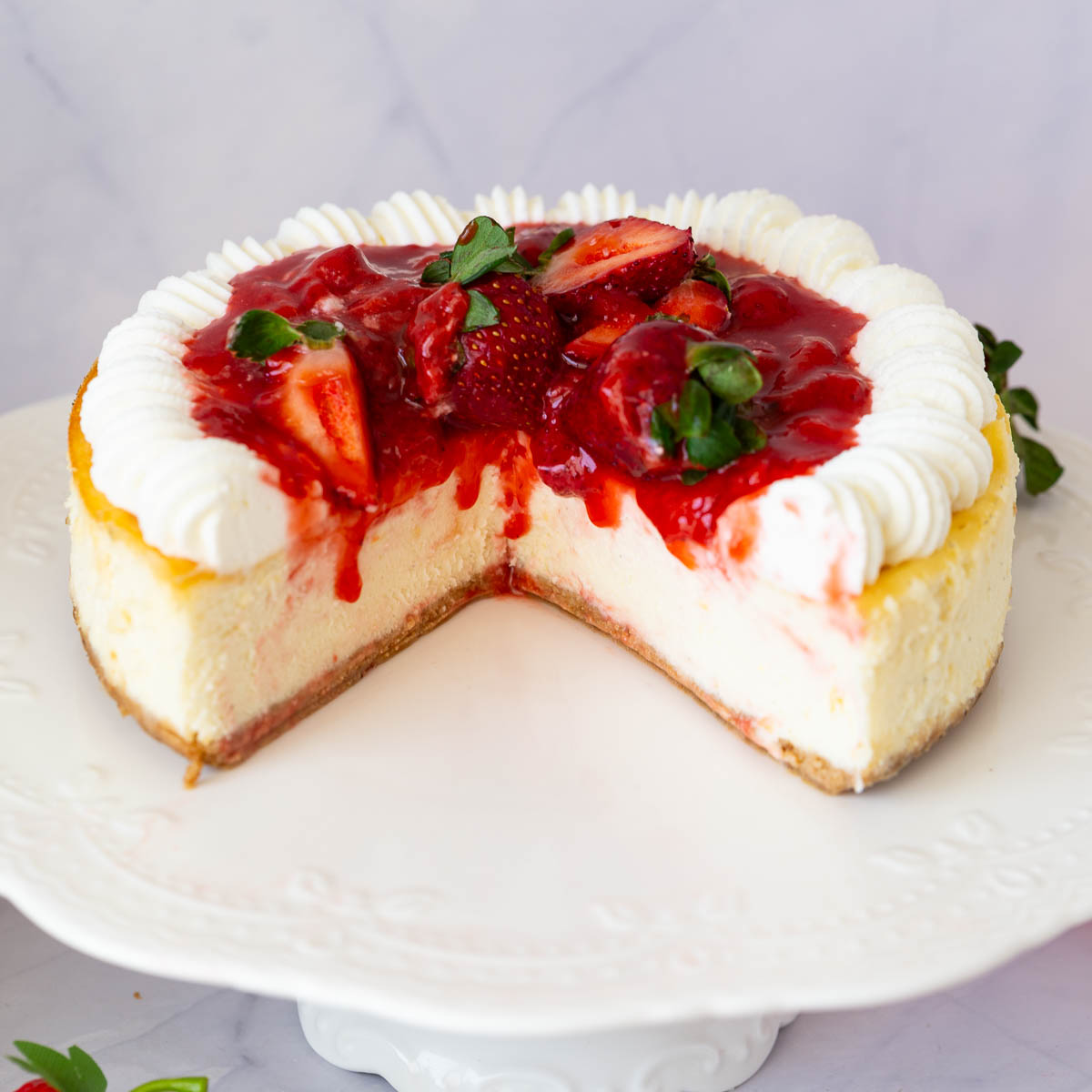 A strawberry cheesecake on the cake stand.