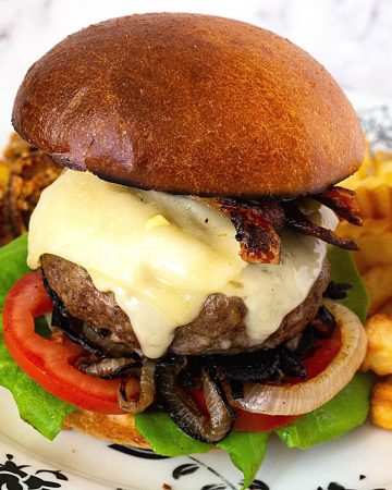 A classic cheese burger on a plate with fries.