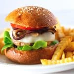 A burger with ground turkey on a place with fries.