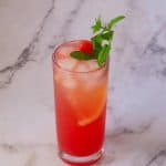 A tall glass with juice made watermelon and lemon.