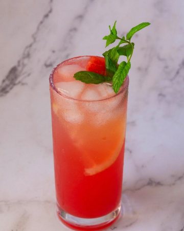 A tall glass with juice made watermelon and lemon.