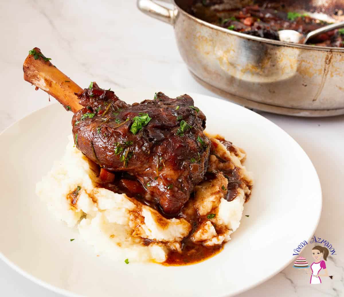 A plate with shank of lamb and red wine gravy.