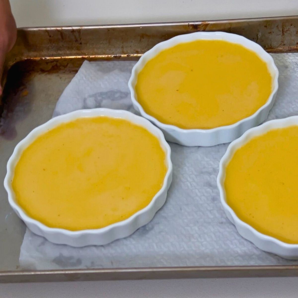 A baking tray with three baked crème brûlée ramekins.