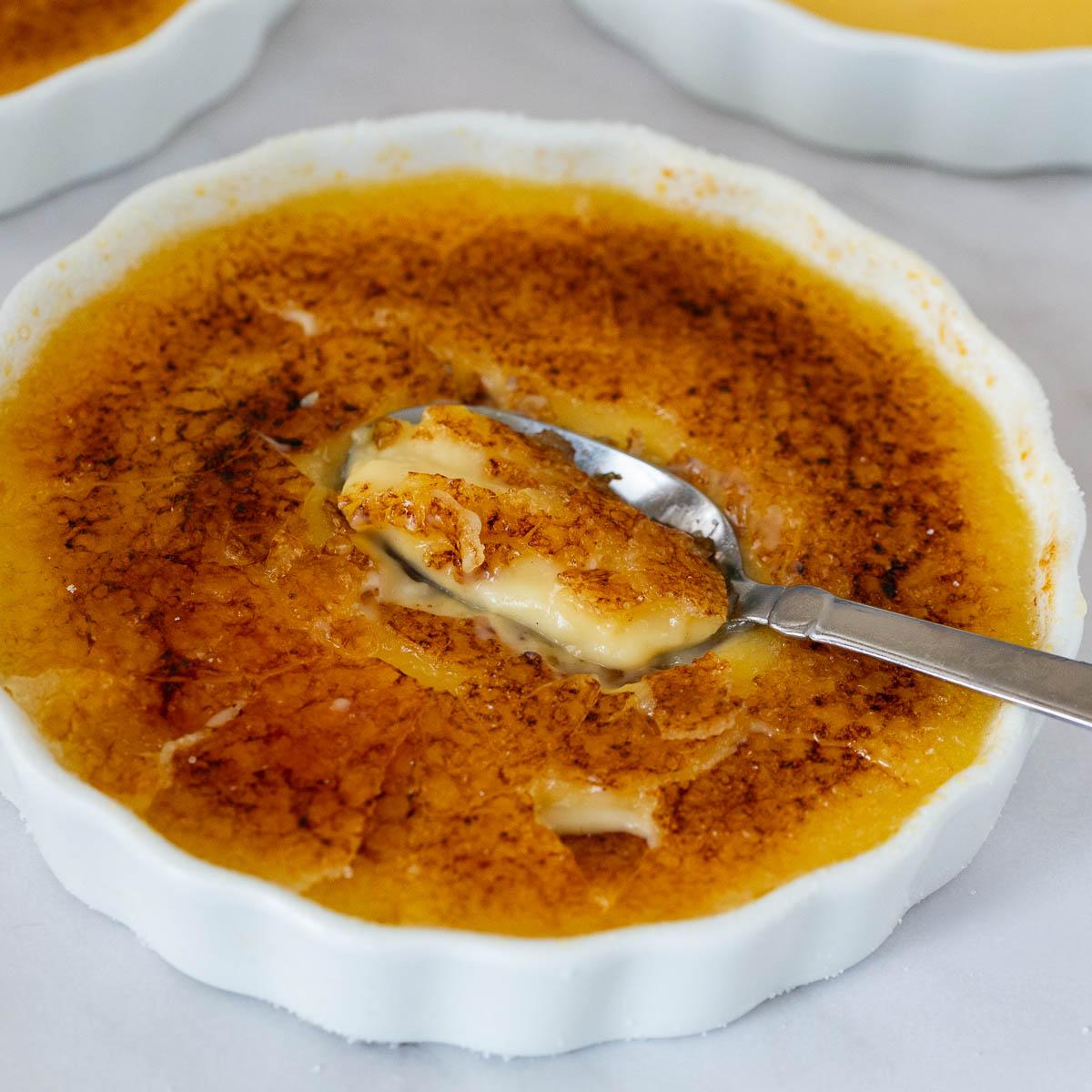 A ramekin with creme brulee and cracked sugar on top.