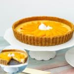 A mango panna cotta tart on a cake stand.