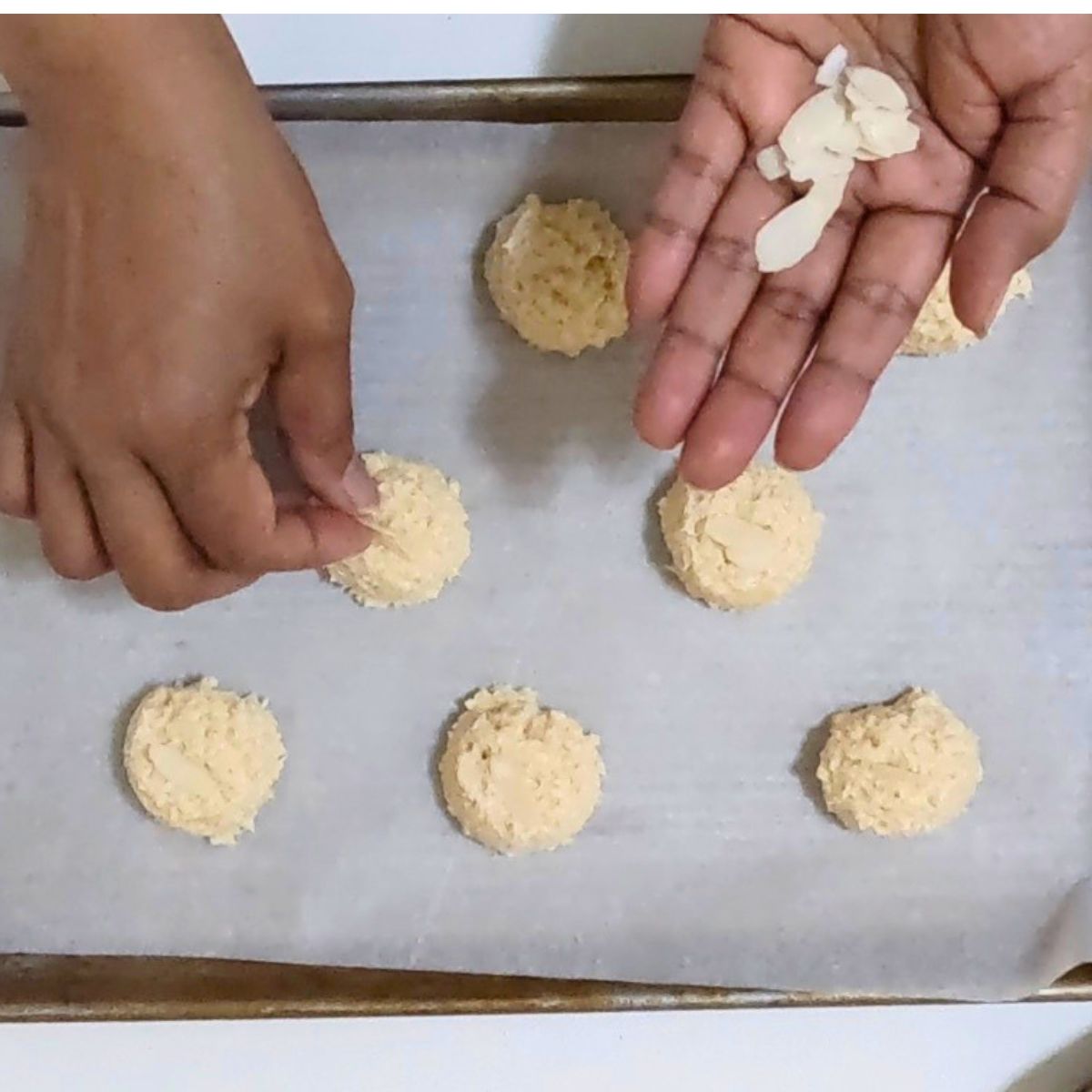 adding flaked almonds on top of macaroons for baking.