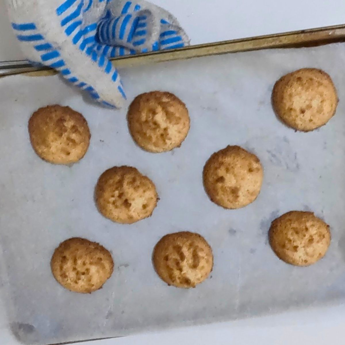Baked gluten free almond macaroons on a baking tray.
