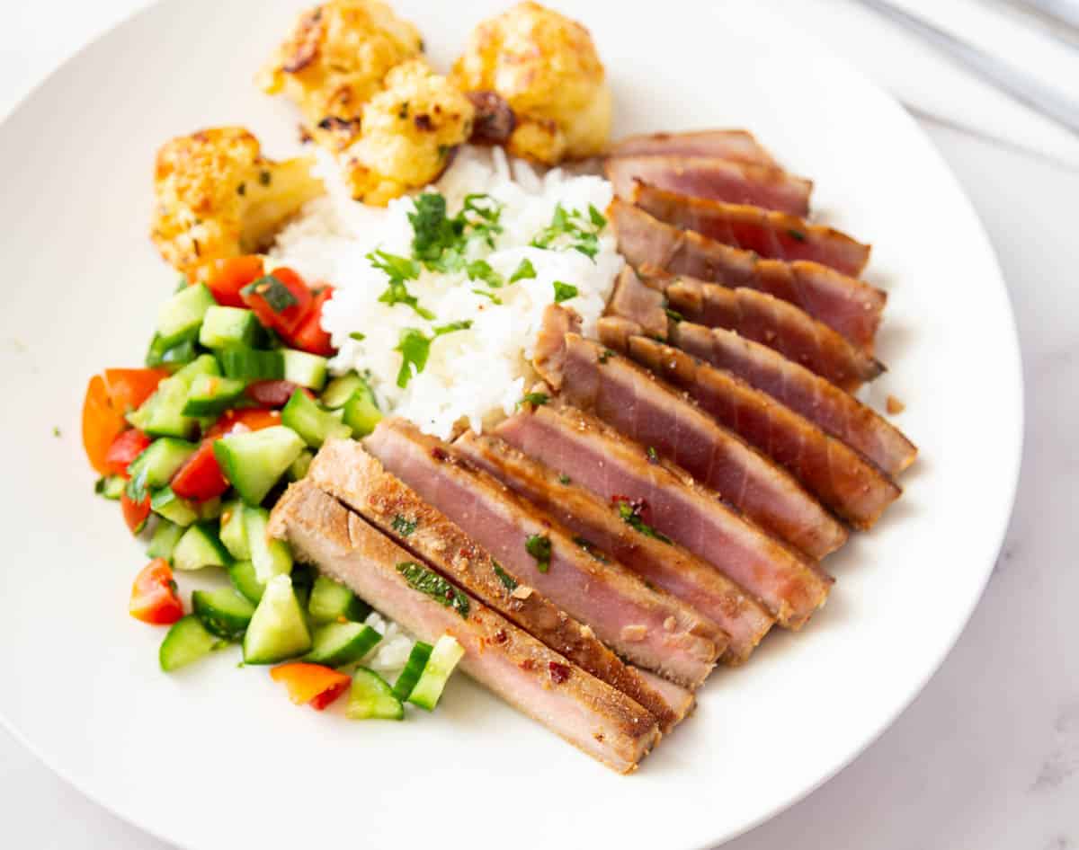 Sliced seared tuna over rice and veggies.