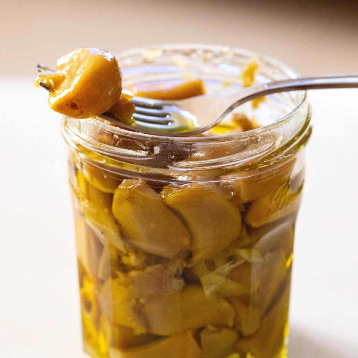 A mason jar and fork with roasted garlic.