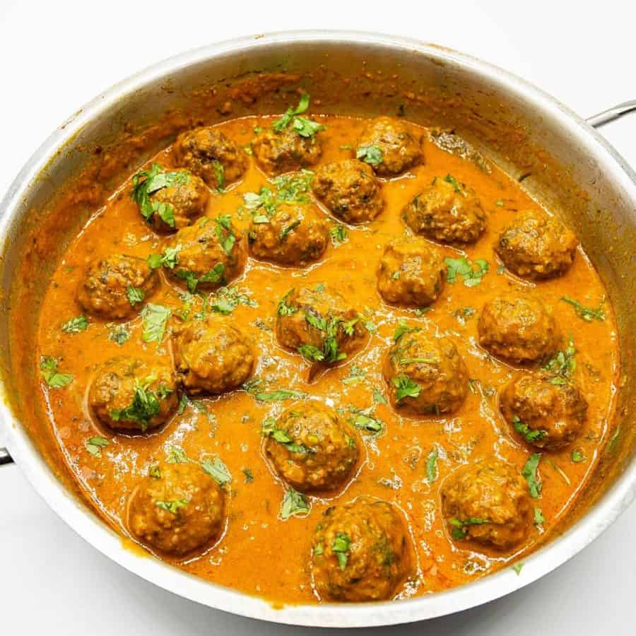 A skillet with curry and meatball kofta.