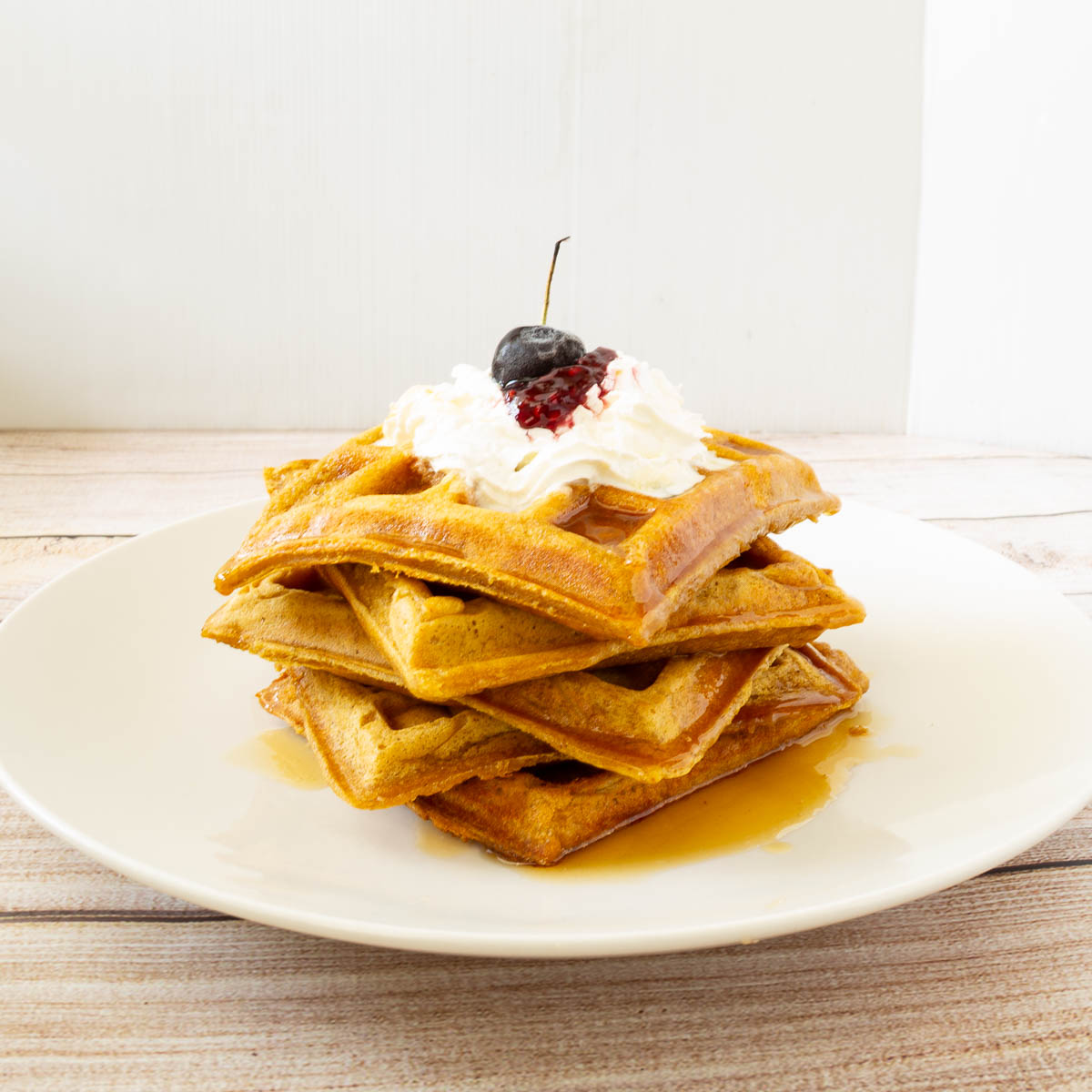 Pumpkin waffles with whipped cream and syrup.