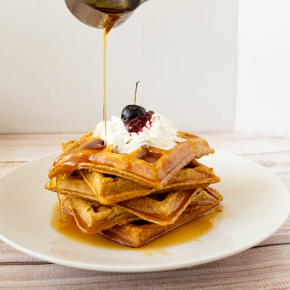 A stack of waffles with maple syrup.