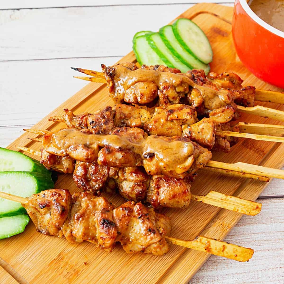 Grilled skewers with chicken and peanut sauce on board.