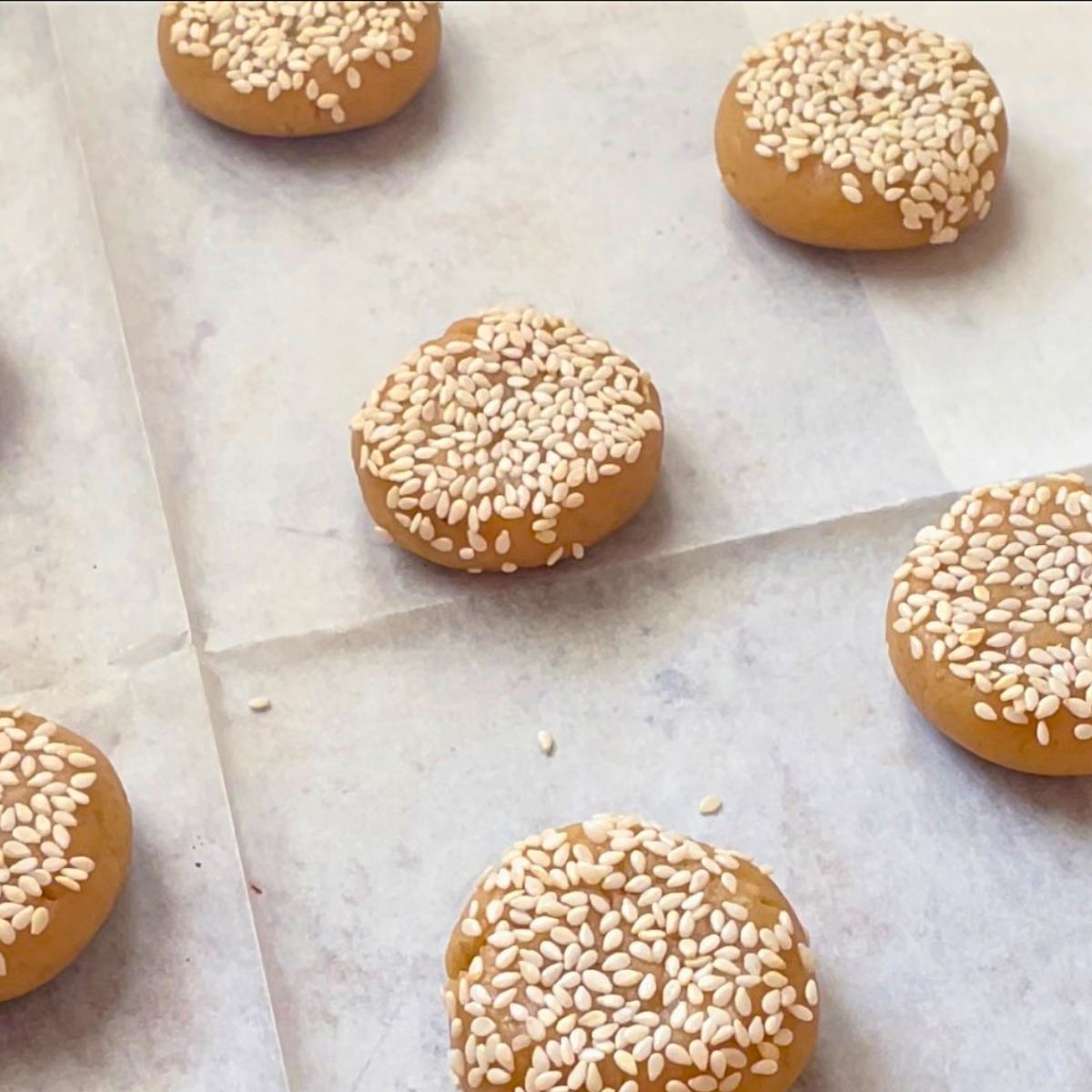 Cookie dough balls with sesame seeds on a baking tray for baking.