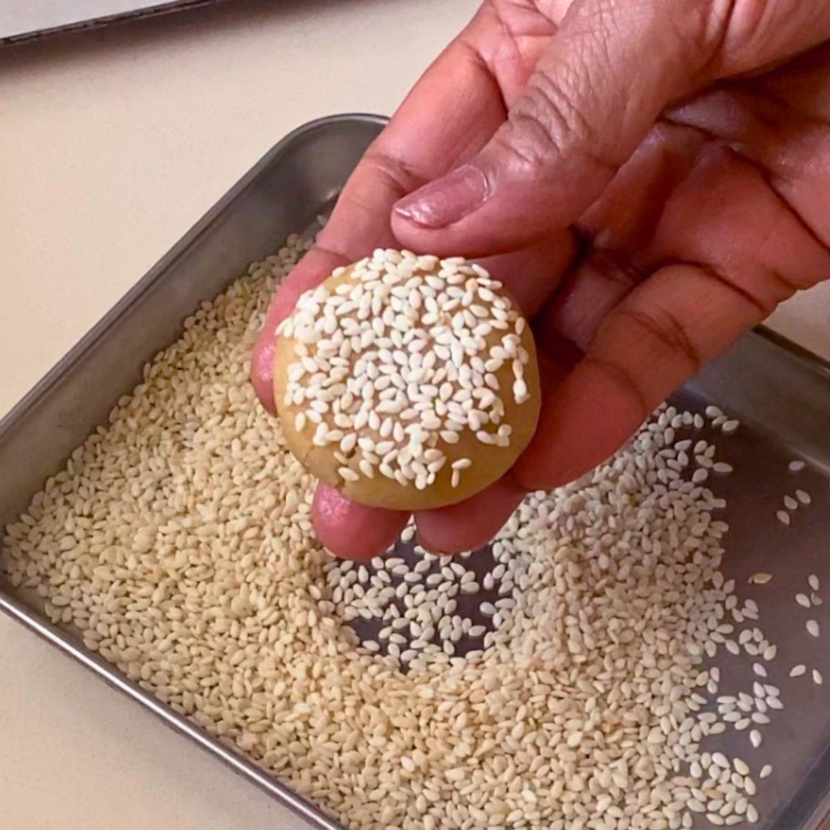 Pressing the cookie dough with sesame seeds for baking.