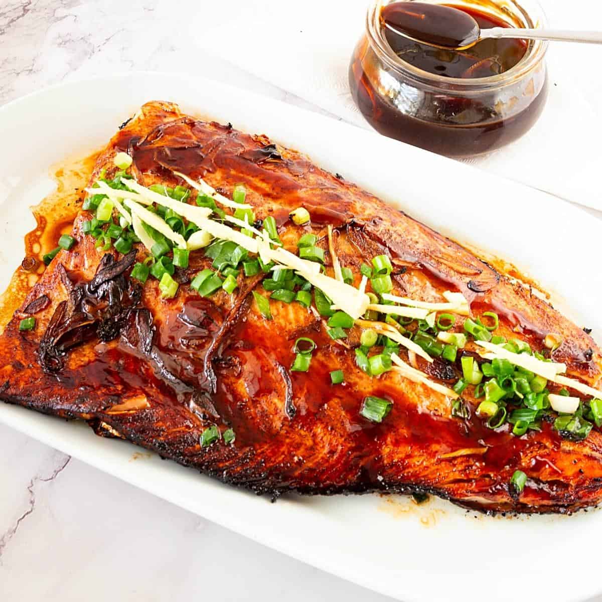 Baked salmon fillet in a platter with teriyaki sauce.