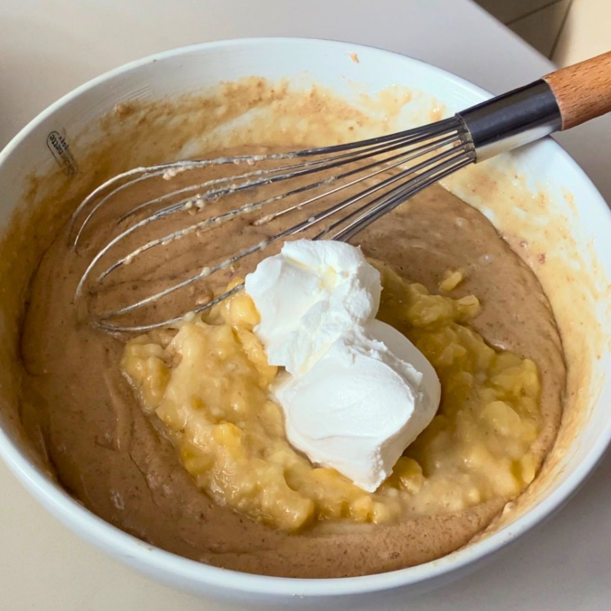 Adding mashed banana and sour cream to the cake batter.